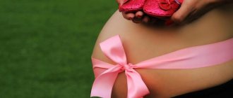 Pregnant woman with bare belly bandaged with pink ribbon holding pink booties