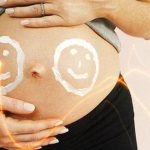 pregnant woman with smiley faces on her belly